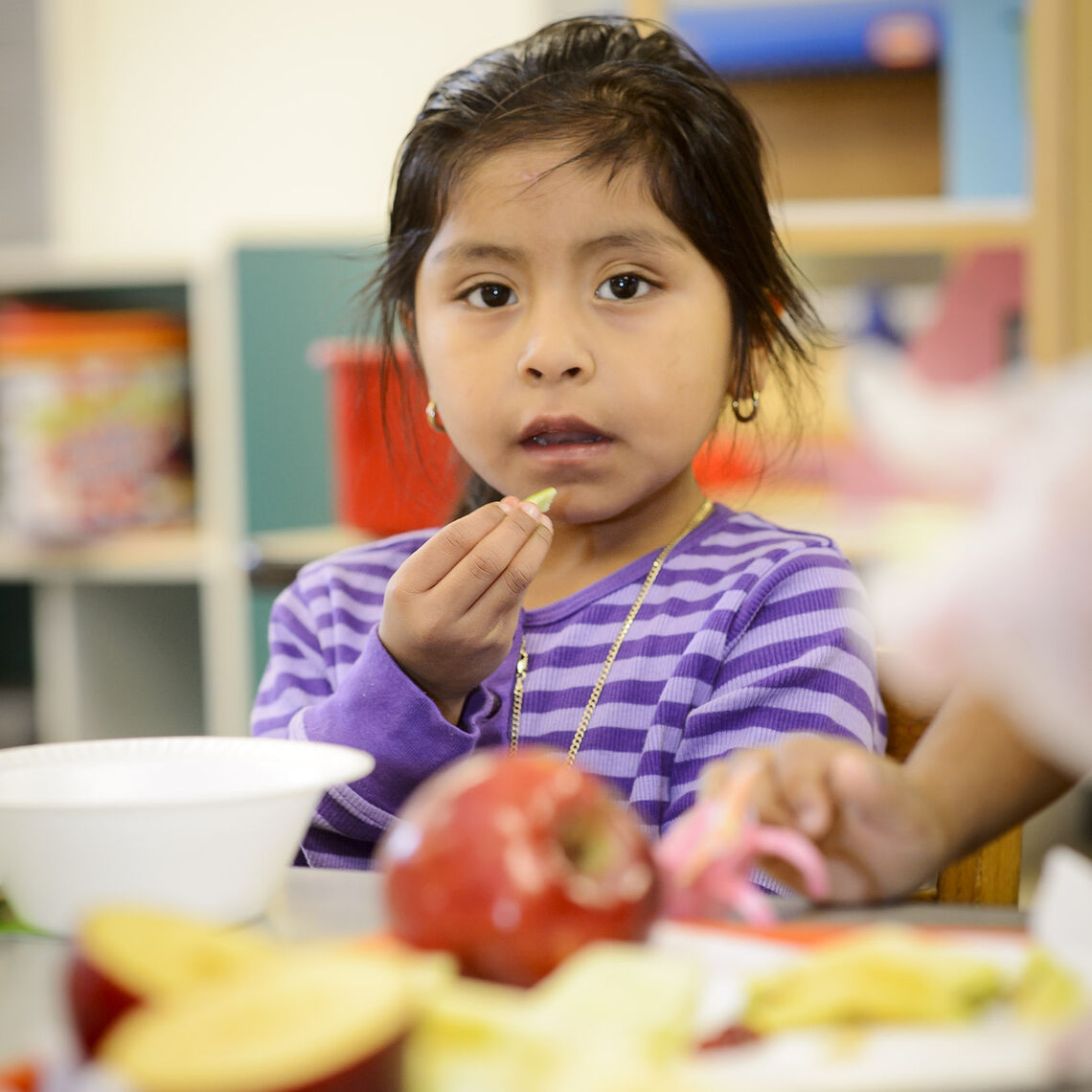 Kindergartener enjoys an apple at her desk