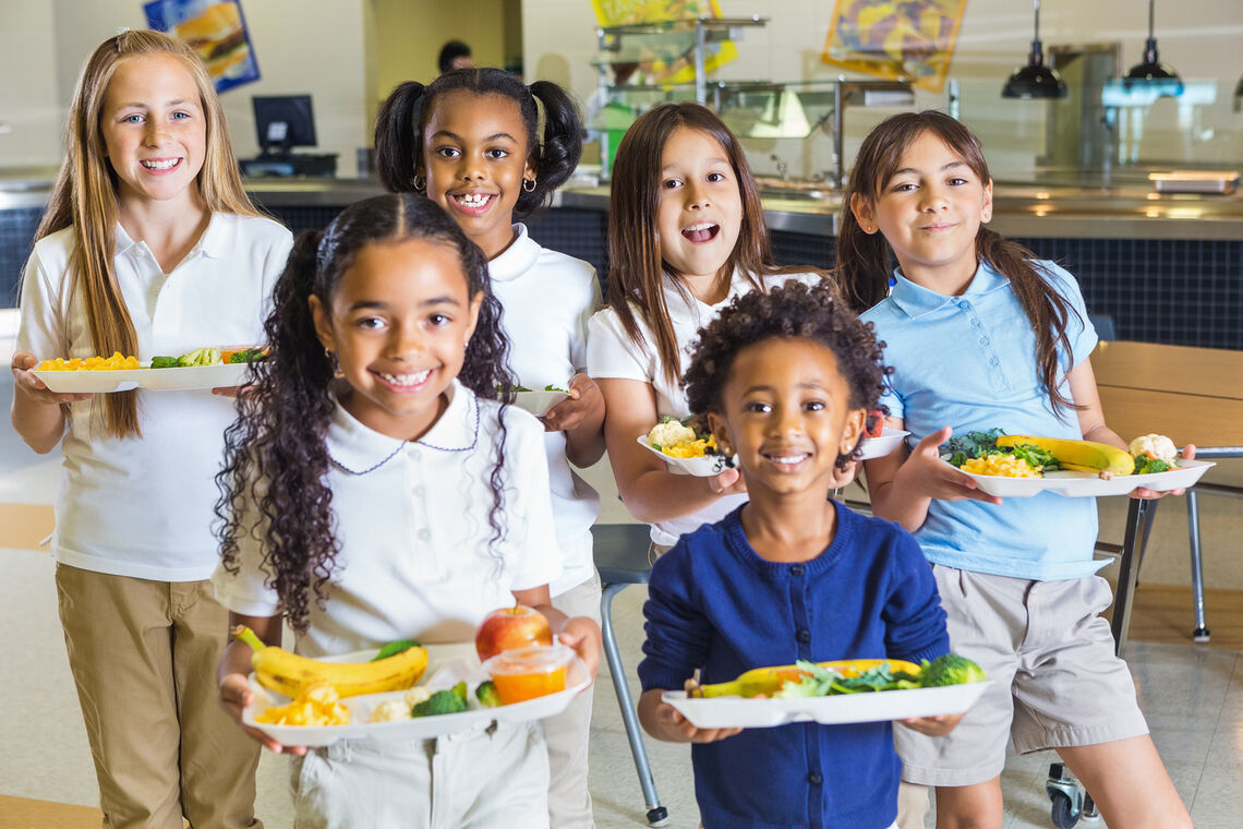 A group of school children holding meals.