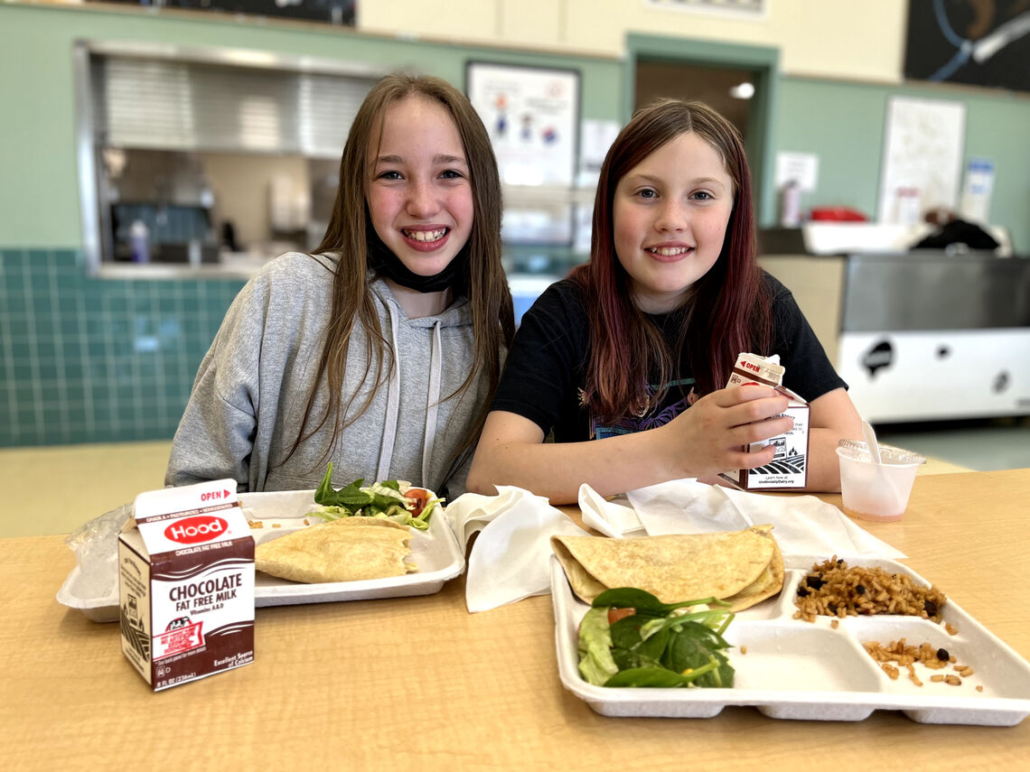 two girls eat school lunch in the cafeteria